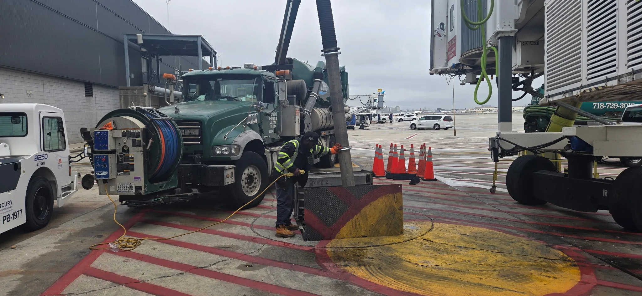 A&L technician in hi-vis working a JetVac hose into an apron drain at an airport gate